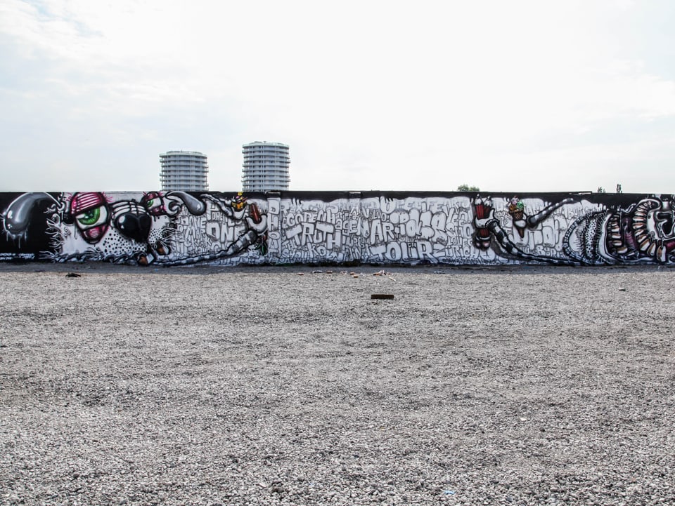Ein Graffitik an einer langen tiefen Mauer.