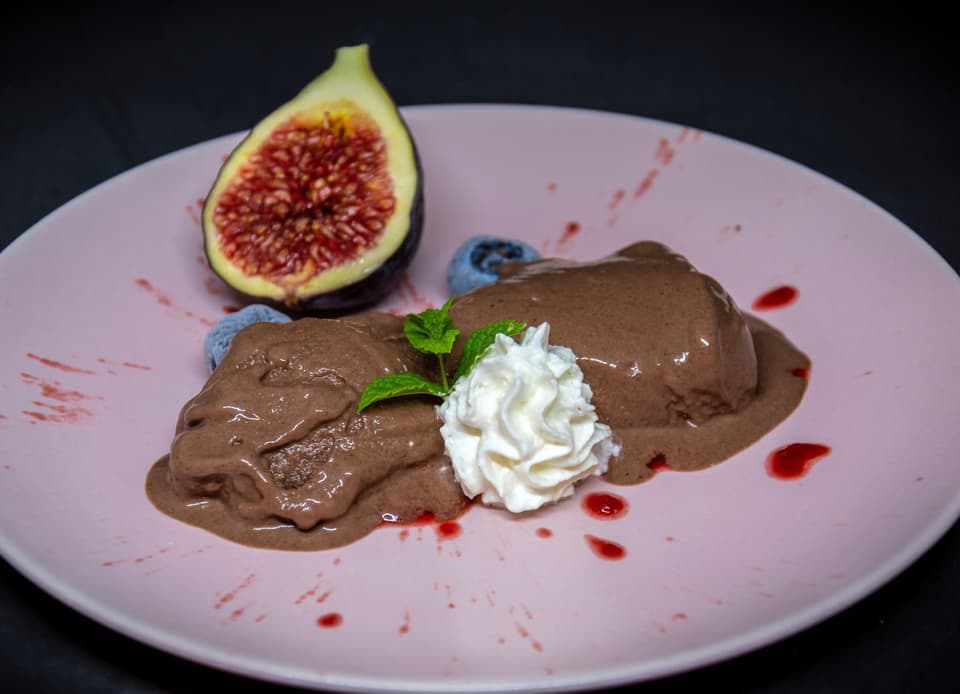 Ein schoko-braunes Eis auf dem Teller, garniert mit Feigen.