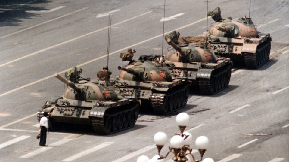 Ein Mann mit Aktentasche stellt sich vier chinesischen Panzern entgegen.