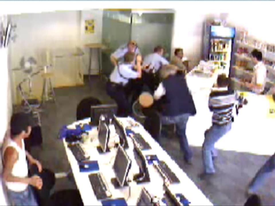 Blick in das Internet-Café, mehrere Beamte versuchen, dem Täter die Waffe zu entreissen.