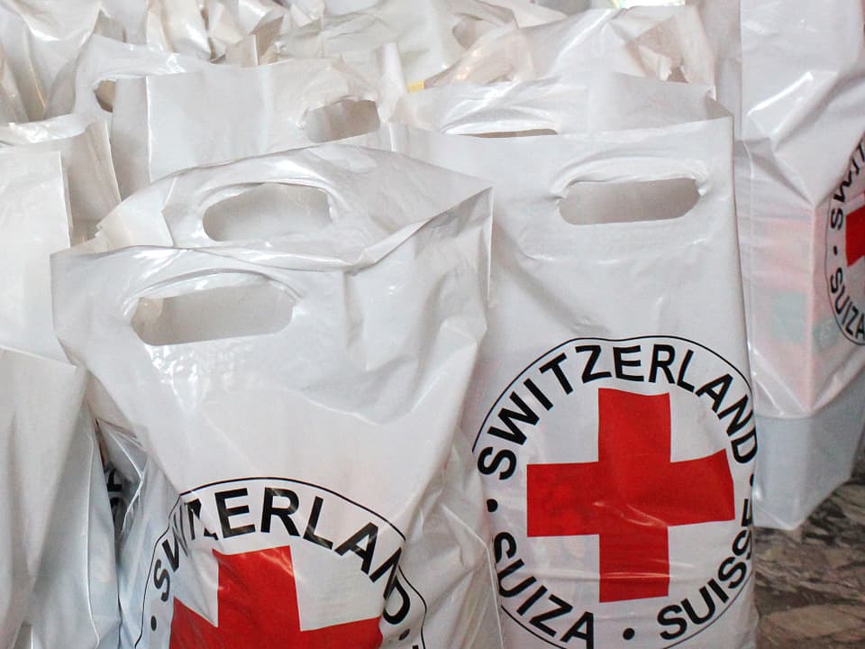 Weisse Plastiksäcke mit einem Roten Kreuz.