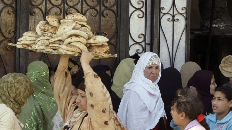 Eine ägyptische Frau trägt Brot durch eine Menschenmenge.