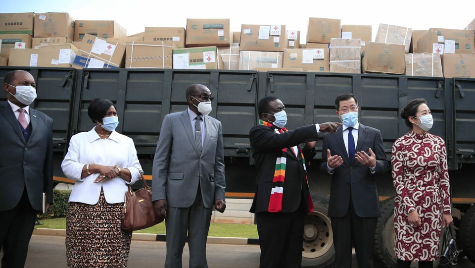 Chinesen und Afrikaner vor einem Wagen mit Hilfspaketen.