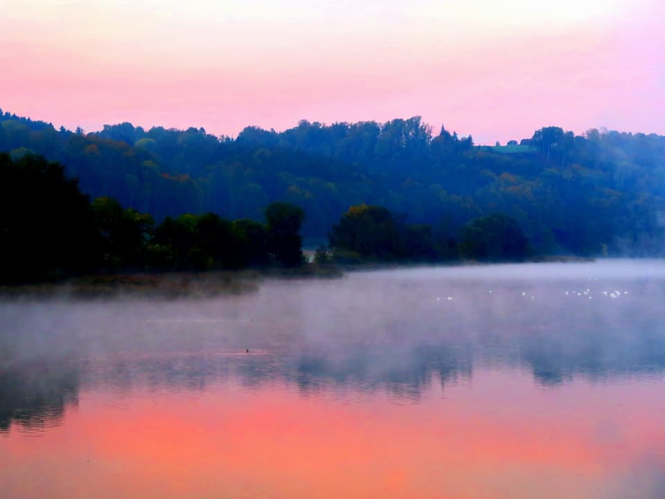 Bild in Rosatönen mit See, der Rauch auf der Oberfläche hat. 