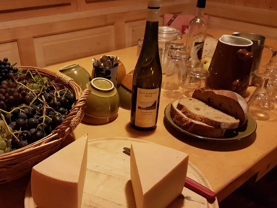 Trauben, Wein, Käse, Brot und Geschirr auf einem Tisch.