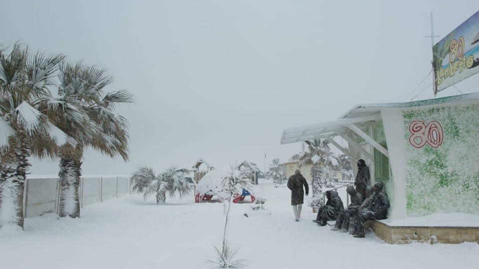 Bild schneebedeckte Wiese, links schneebedeckte Palmen, rechts läuft eine Gestalt davon, daneben sitzen einige draussen.