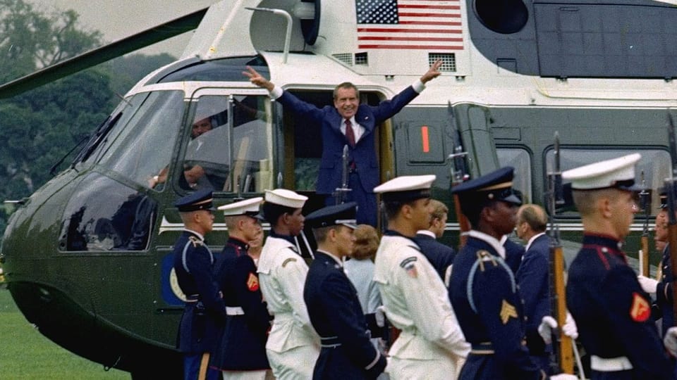 Richard Nixon mit ausgestreckten Armen und die Finger in V-Pose im Eingang eines Helikopters
