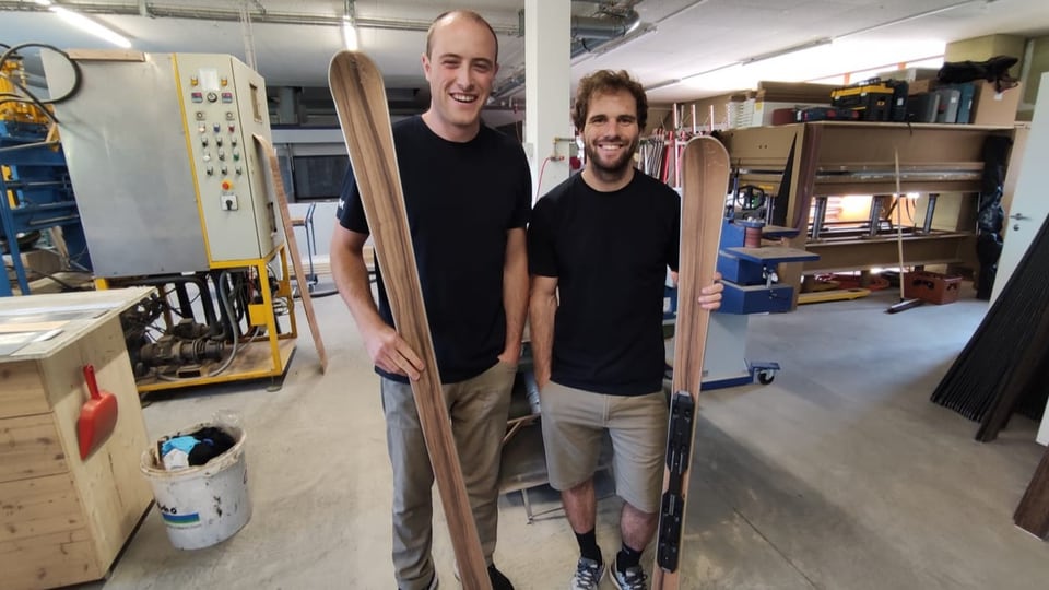Zwei Männer in einer Werkstatt mit je einem Holzski in der Hand