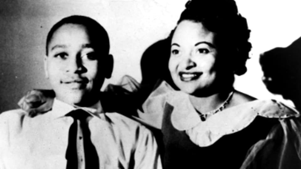 schwarzweiss Foto einer Frau, rechts, mit hochgestecktem Haar, lächelt, und einem Jungen, links, lächelt, trägt Krawatte