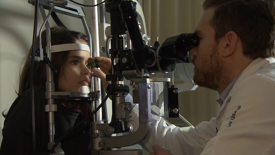 Ein Augenarzt untersucht das Auge eines kleinen Mädchens.