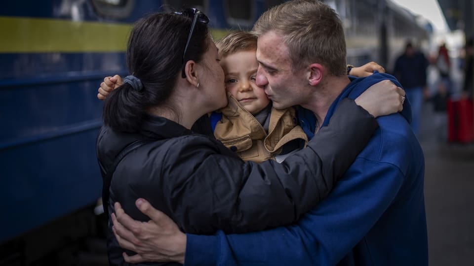Vater umarmt Frau und Tochter, die nach Kriegsbeginn mit Zug aus Kiew flüchten.