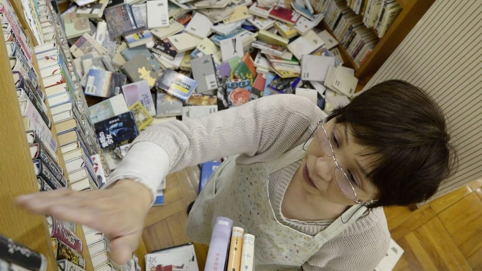 Eine Frau sortiert Bücher in ein Regal
