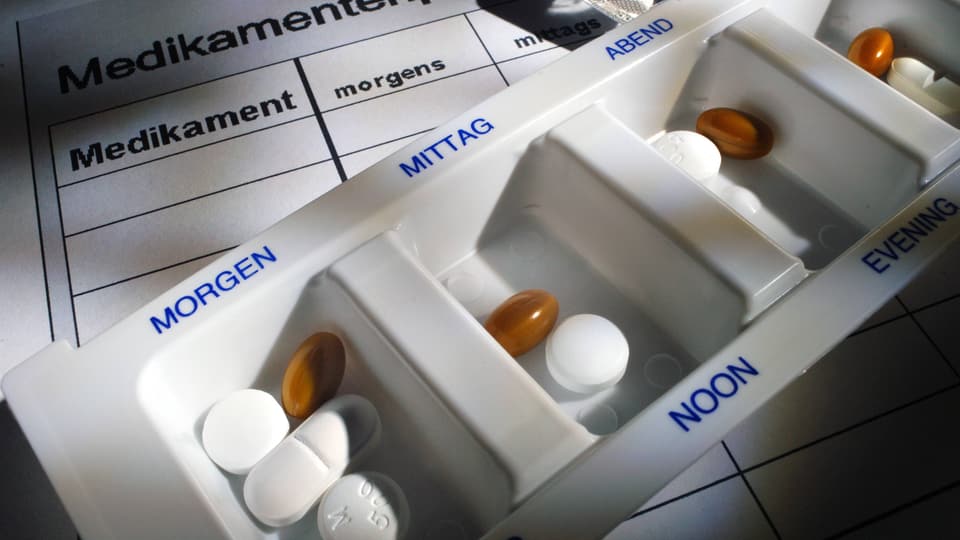 Eine Medikamentenbox mit Inhalt auf einem Medikamenten-Einnahmeplan.