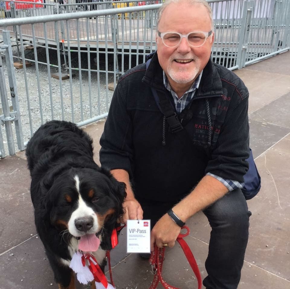Mann mit Hund, der Hund trägt einen VIP-Pass am Hals