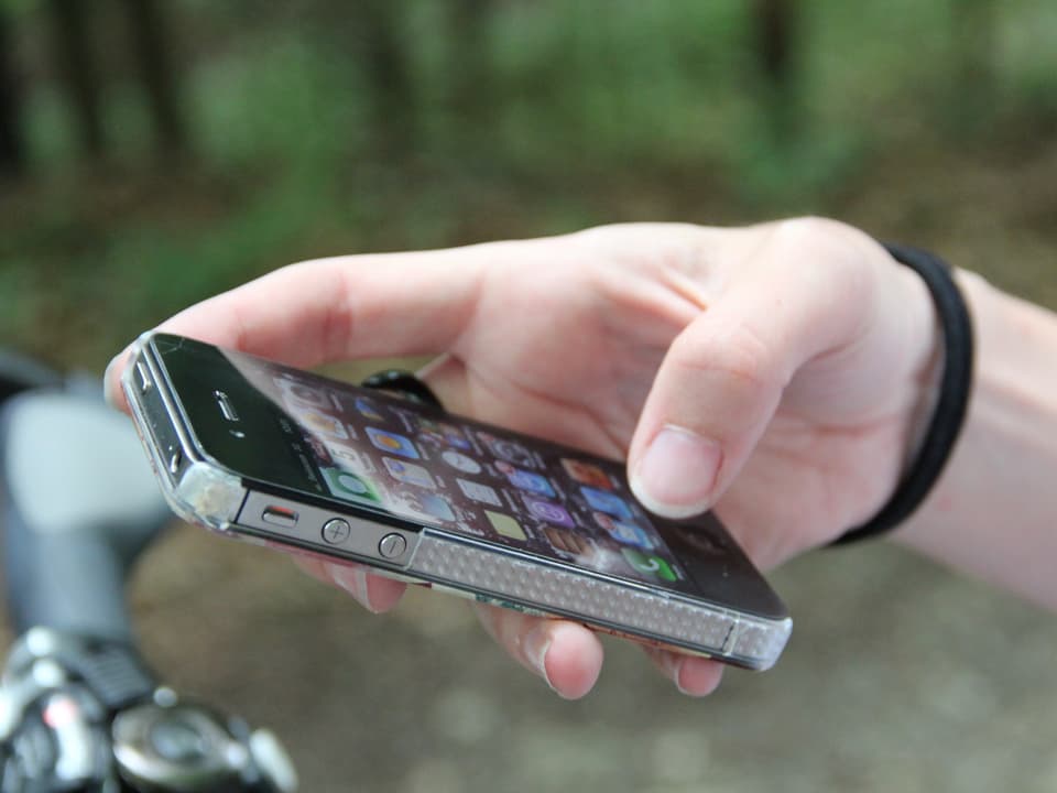 Die Hand einer Wanderin mit den Daumen auf dem Nachrichten-App eines iPhones.