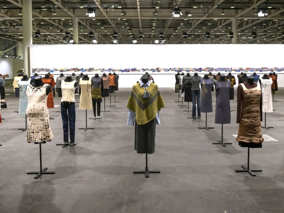 Duzende Schneiderpuppen mit unterschiedlichen Kleidern stehen in einer riesigen Halle.