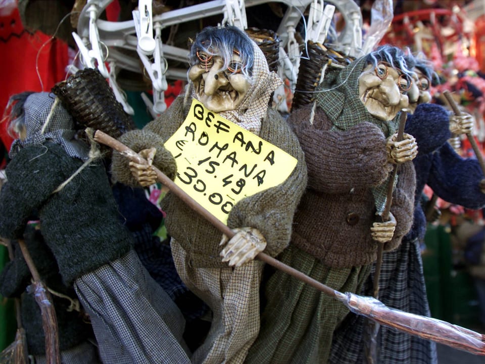 Ein paar Befana-Puppen hängen an einem Stand zum Verkauf.