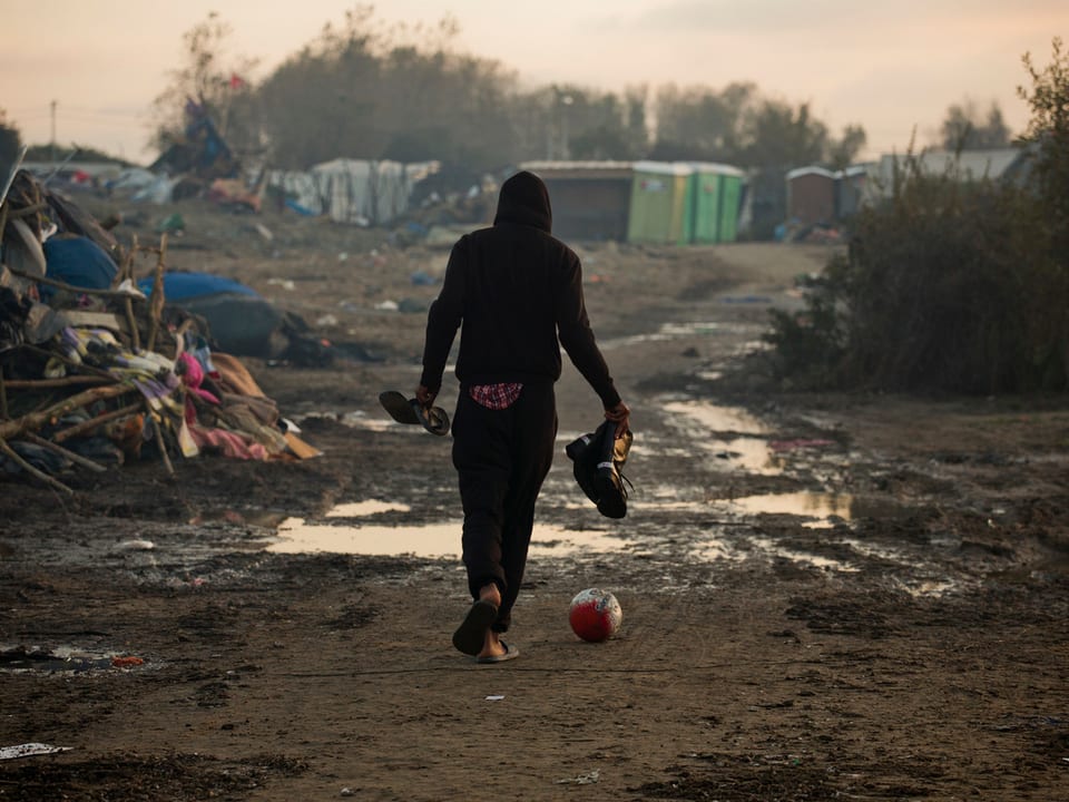 Migrant kickt einen Fussball im Lager von Calais (Ende 2016). 