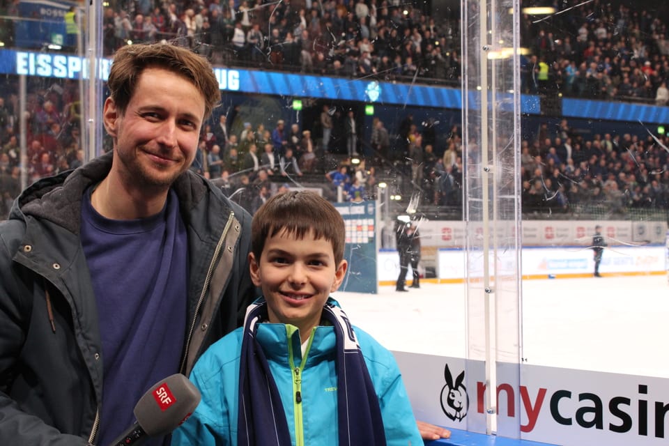 Ein Mann und ein Junge, im Hintergrund ein Eishockeyfeld