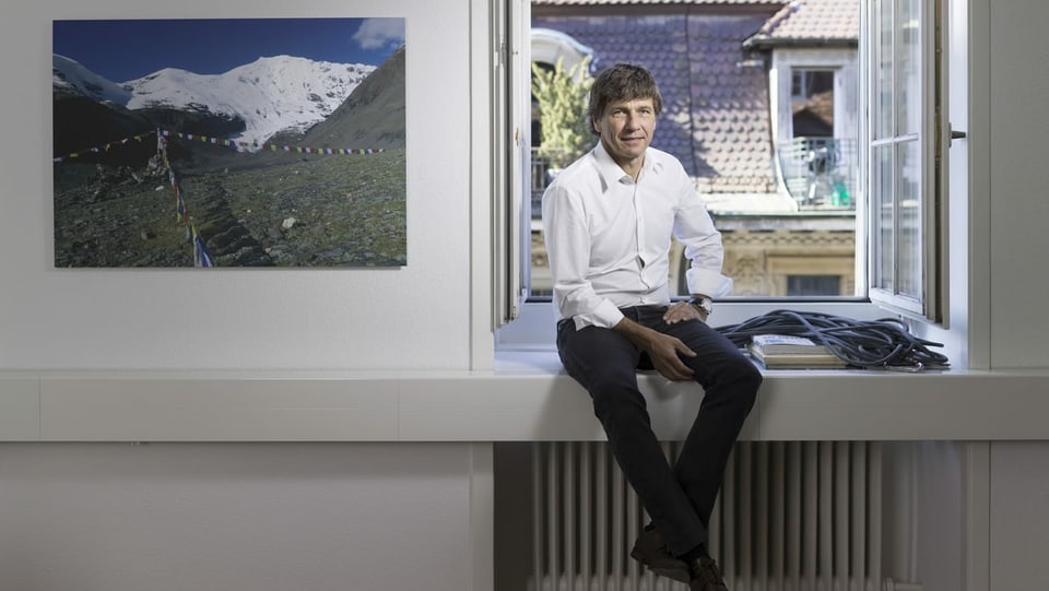 Andre Lüthi sitzt in seinem Büro auf dem Fenstersims und blickt in die Kamera.