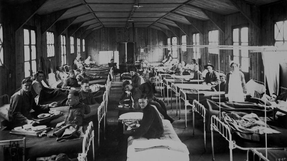 Viele Menschen auf Krankenbetten in einer Halle