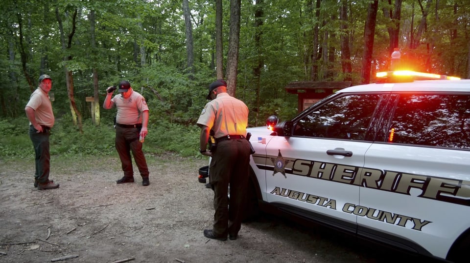 Sheriff-Fahrzeug und Ermittlungsbeamte auf einem Waldweg