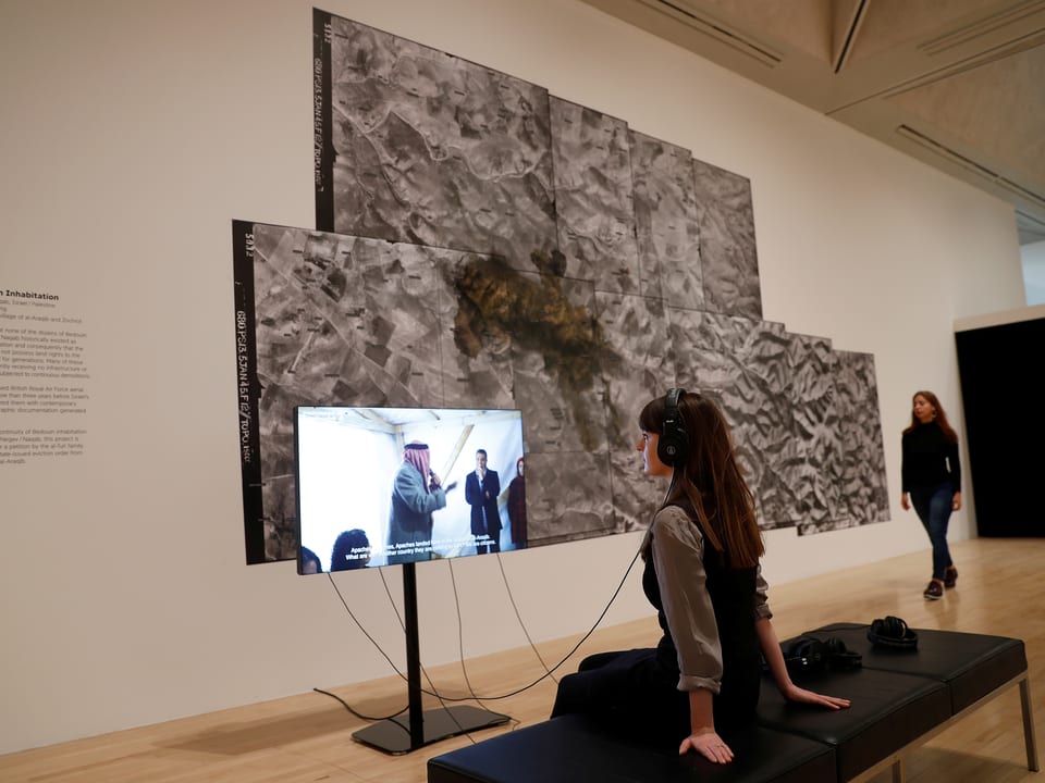 Eine Frau schaut sich die Arbeit von Forensic Architecture im Tate Modern an.