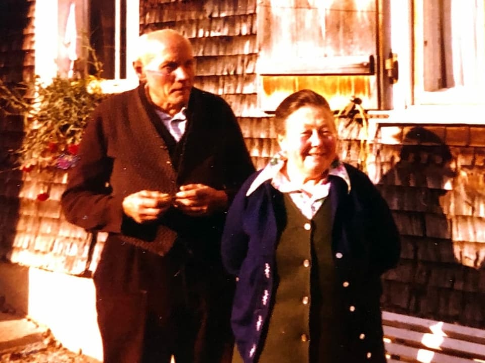Ein älteres Ehepaar vor einem Haus.