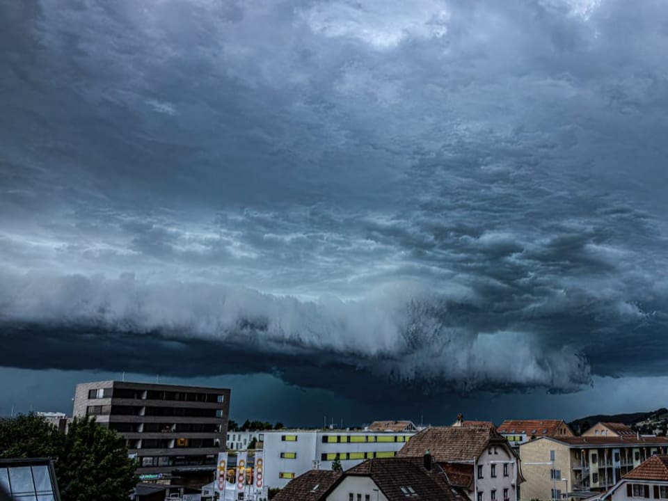 Dunkle Gewitterwolke zieht über Dorf