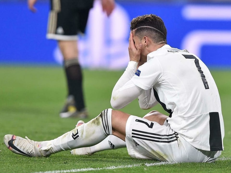 Cristiano Ronaldo sitzt enttäuscht am Boden.