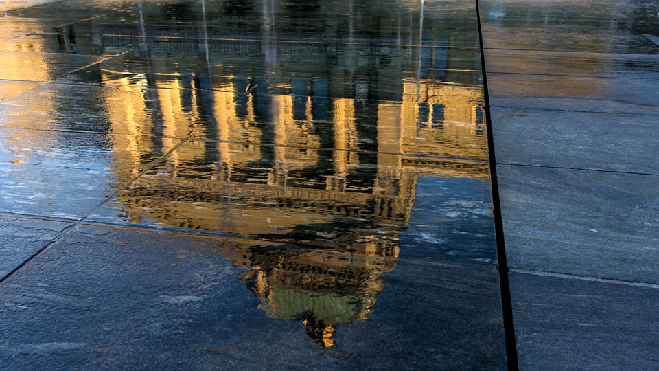 Spiegelung des Bundeshauses in einer Wasserlache.