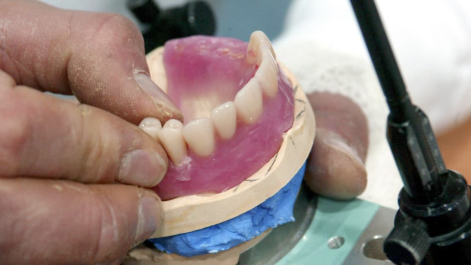  Ein Zahntechniker fertigt einen totalen Zahnersatz an