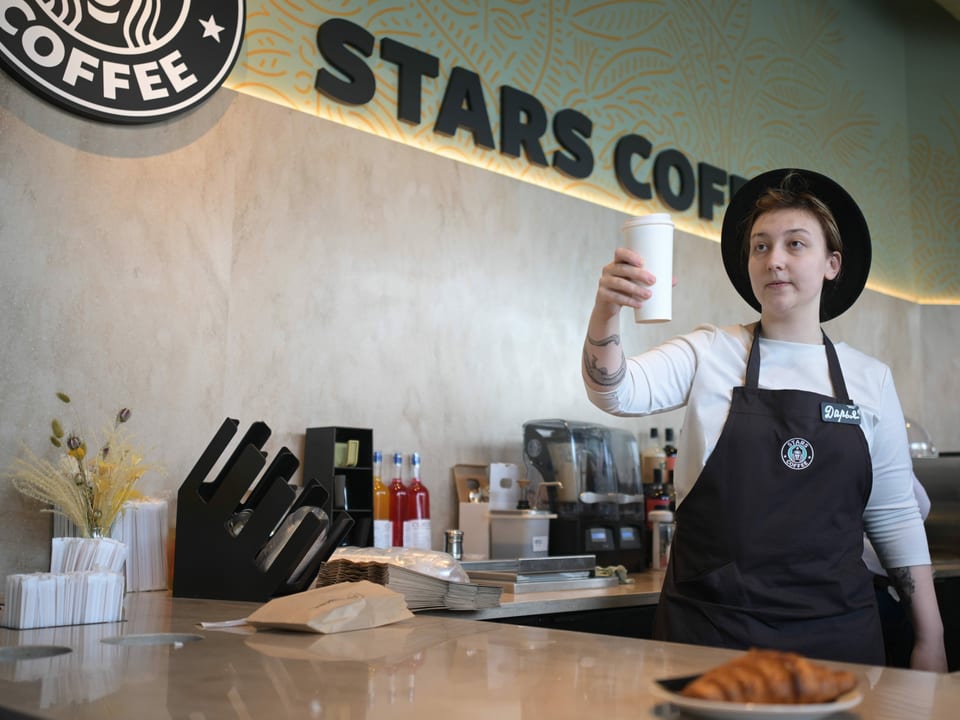 Star Coffee Barista hält einen Kaffeebecher.