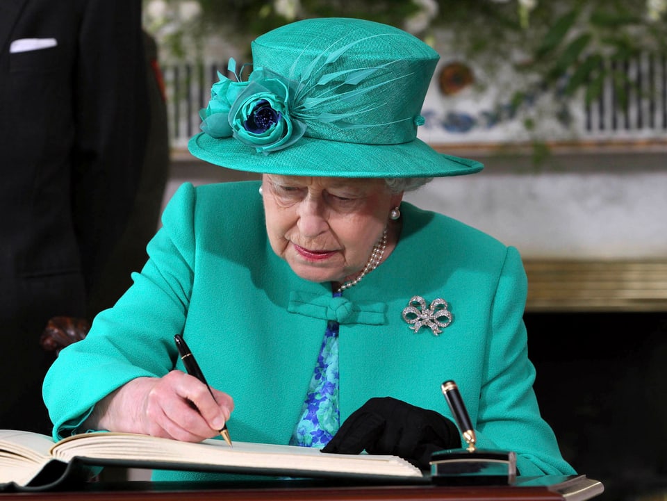 Queen Elisabeth II schreibt etwas in ein Buch