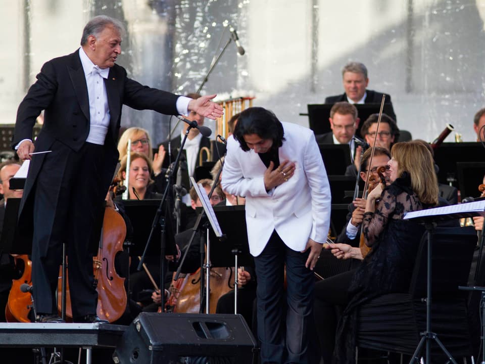 Dirigent Zubin Mehta im scharzen Frack, neben ihm der Komponist Abhay Rustum Sopori mit weissem Jacket.