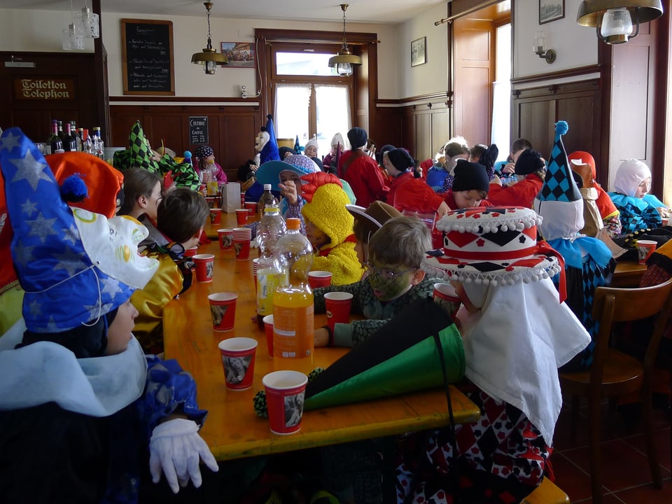 Eine Gruppe verkleideter Kinder sitzt in einem Restaurant an verschiedenen Tischen. 