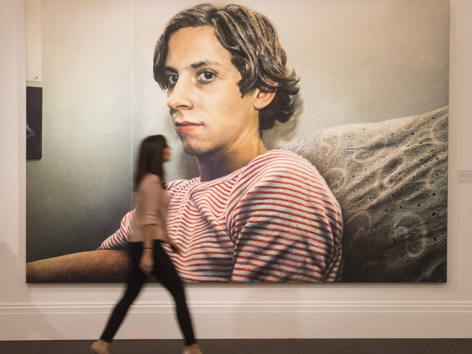 Woman pasting drawings of boy in striped shirt