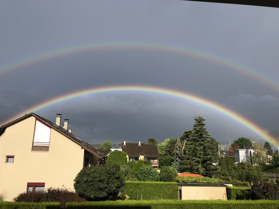 Doppelter Regenbogen über einem Einfamilienhausquartier.