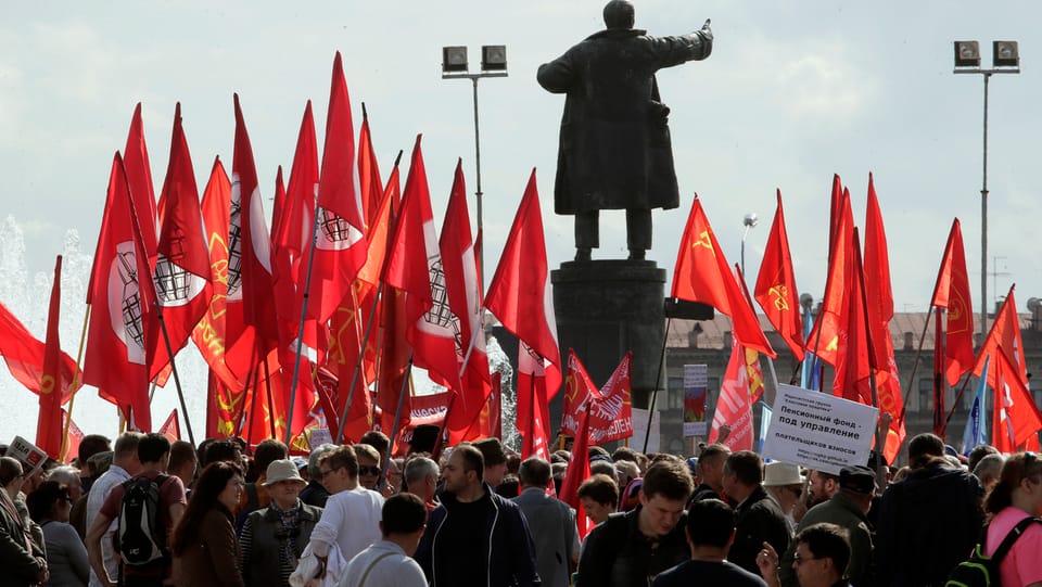 Demonstranten stehen um eine Lenin-Statue