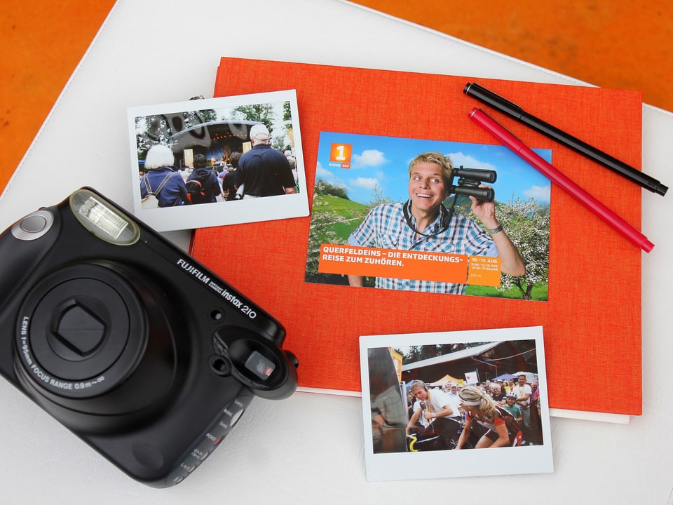 Das Tagebuch mit Stiften und einer Polaroidkamera und zwei Fotos.