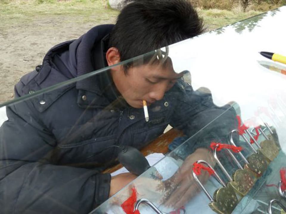 Chinese mit Zigarette im Mund verkauft Liebesschlösser