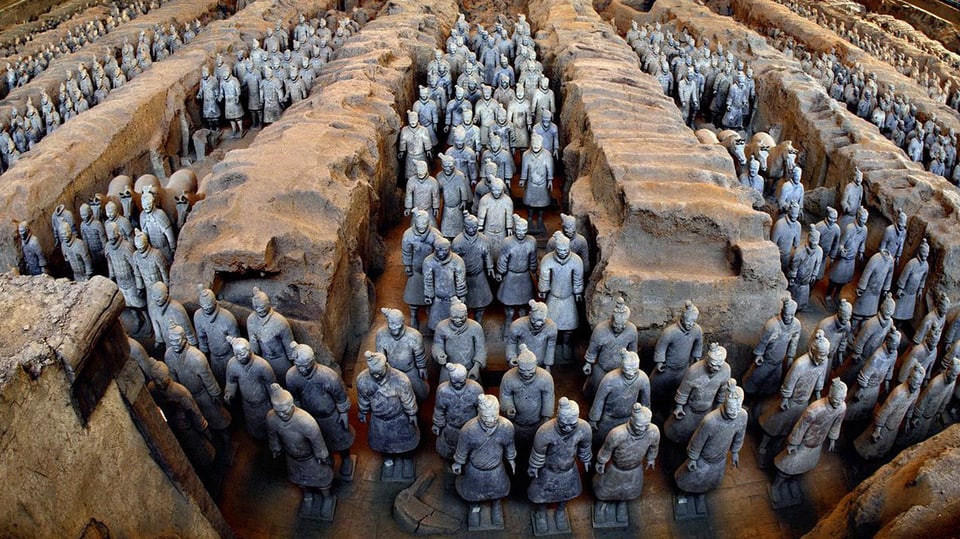 Unzählige tönerne bläuliche Soldaten stehen zwischen zwischen grossen Felsen aufgereit.