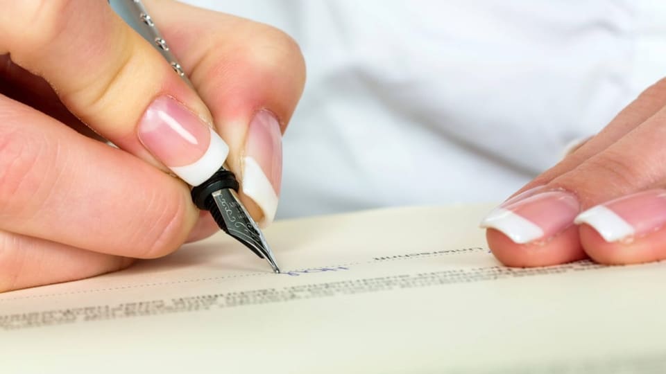 Eine Frau unterschreibt ein Dokument