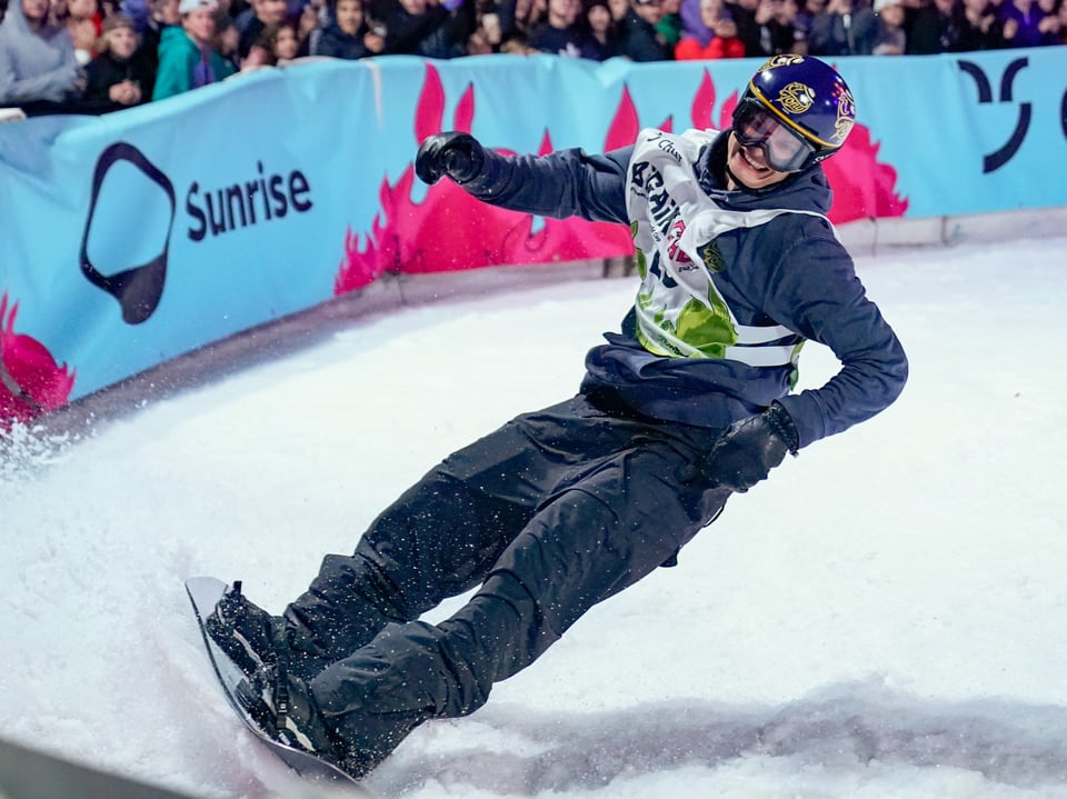 Snowboarder rutscht bei einem Wettbewerb auf einem Schneehang.