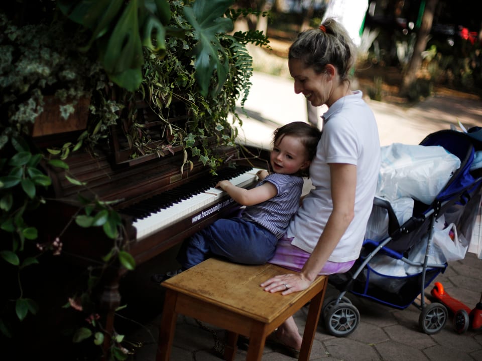 Eine Mutter sitzt an einem Klavier in einem Stadtpark von Mexiko.
