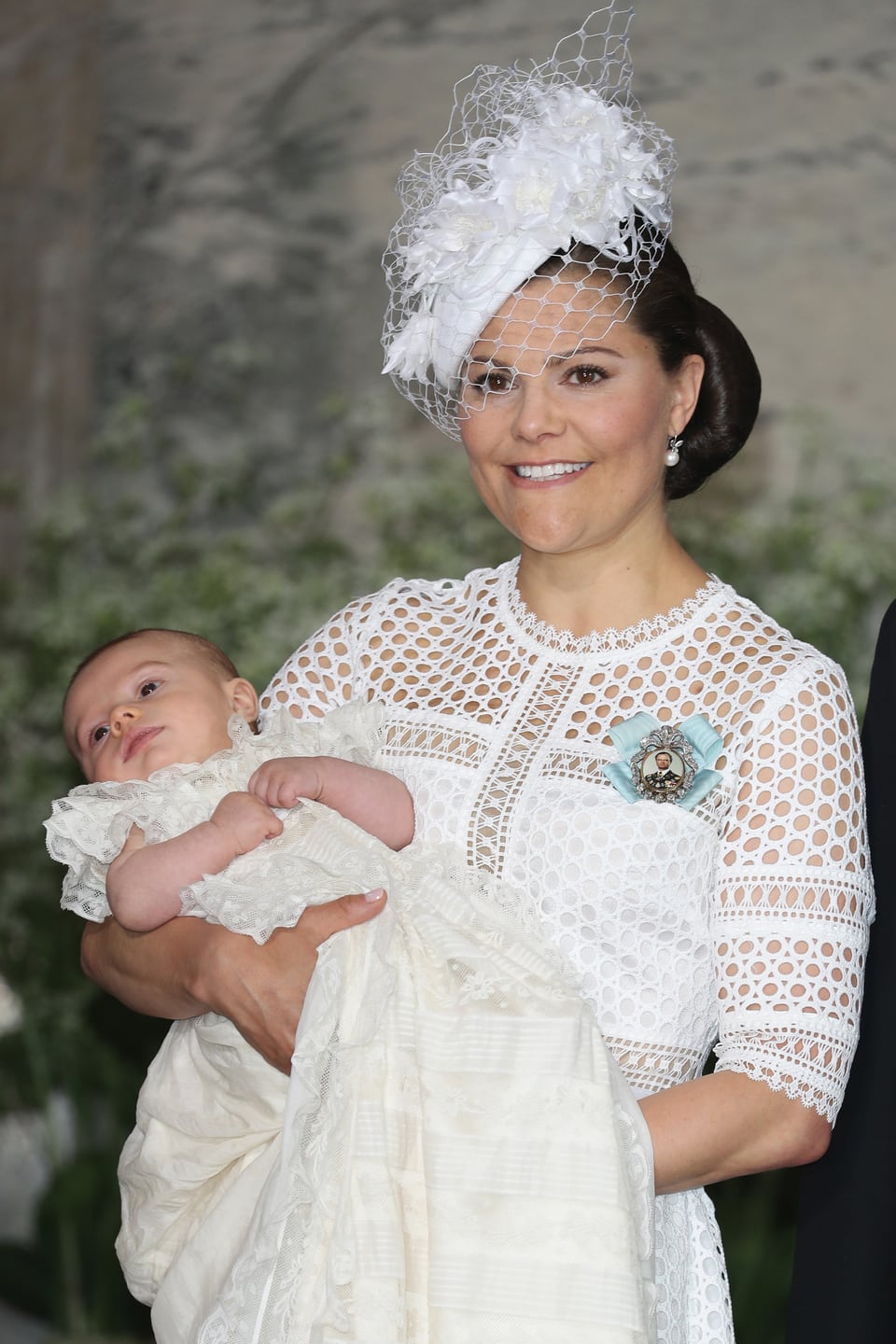Victoria mit Baby Oscar auf dem Arm, beide festlich gekleidet