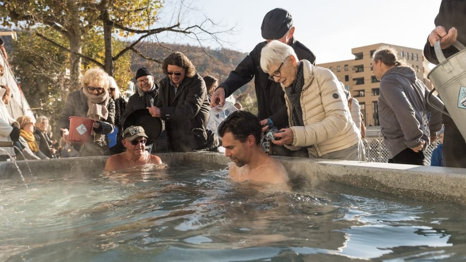 Menschen baden in einem Thermalbad an der Strasse.