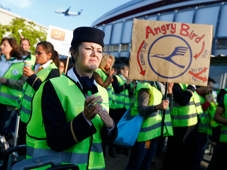 Eine Lufthansa-Angestellte hält ein Schild mit der Aufschrift "Angry Bird"