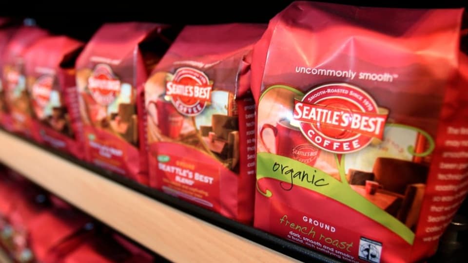 Mehrere rote Kaffeesäcke auf einem Holzablagefach, worauf «Seattle's Best Coffee» steht.