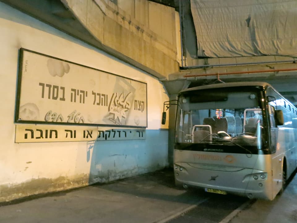 Ein Parkierter Pus neben einem Schild mit hebräsichem Schriftzug.